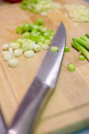 Kitchen knife and vegetables on a wooden cutting board in the kitchen, preparing and cutting the vegetables while cooking a healthy mealの写真素材