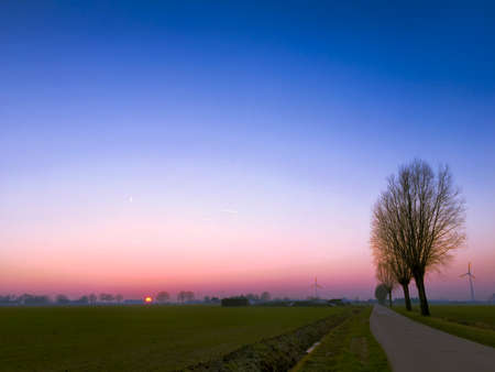 Dramatic colorful countryside sunrise with trees and silhouettesの写真素材