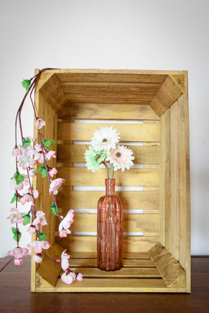 Spring flowers, gerbera or daisy, in a vintage pink vase inside an old wooden fruit crateの写真素材