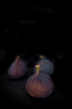Beautiful fresh blue violet figs on dark stone background with empty copyspace close up vie from above.の写真素材