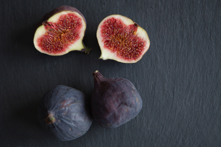 Beautiful fresh blue violet figs on dark stone background with empty copyspace close up vie from above.の写真素材