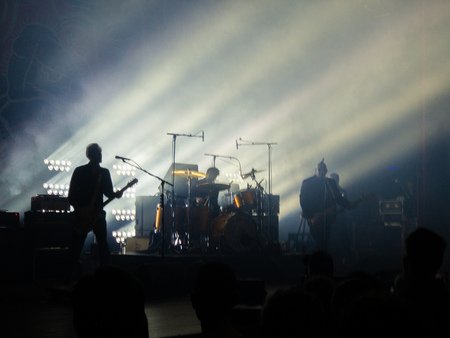 Silhouettes of a crowd of people in front of a well backlit stage on which a rockband is performingの写真素材