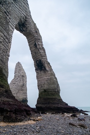 The needle in the chalk cliffs of the Normandy coast of Etretat, France, on a grey misty dayの写真素材