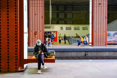 Antwerp, Belgium, May 2019, Man using smartphone at railway platform waiting for train