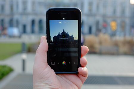 Detail view of a persons hand holding a smartphone device taking up photos of a monument cathedralの写真素材