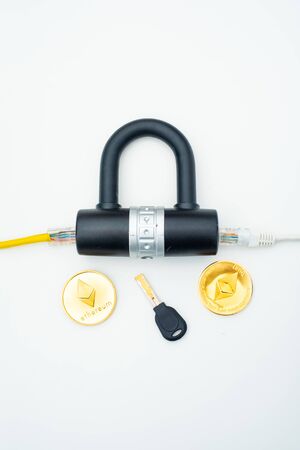 Two computer network cables going through a lock with a key and a crypto currency coin, depicting digital security, cybersecurity or internet securityの写真素材