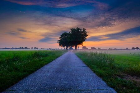 Colorful glowing sunrise over a countryside farming area, creating an idyllic scenic landscapeの写真素材