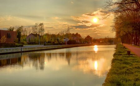 Dramatic and mesmerizing colorful sunset or sunset sky with horizon over Flemish canal in Belgiumの写真素材