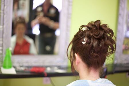 Hairdresser doing a womans hair in professional hairdressing salon or barbershop , seen from behind...