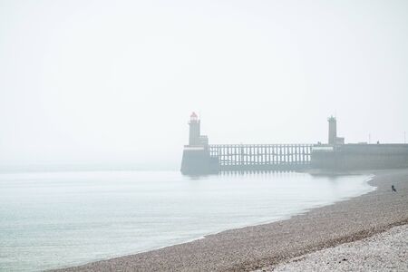 The lighthouses that form a beacon in the port of Fecamp, Normandy, France on a grey and misty dayの写真素材