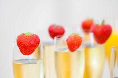 Glasses of sparkling wine or champagne and strawberry on a blurry background during some sort of festivity or celebration such as a wedding, borthday or newyearの写真素材