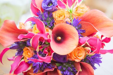 Close up with a colorful vivid mix of spring flowers of calas, zantedeschia, roses, orchids and more in orange, purple and pinkの写真素材