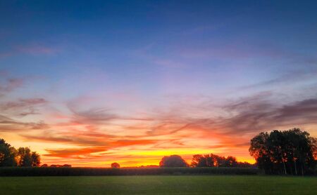 Colorful glowing sunrise over a countryside farming area, creating an idyllic scenic landscapeの写真素材