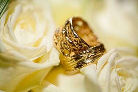 Close-up of two Wedding rings and the wedding bouquet of white roses on a weddings day の写真素材
