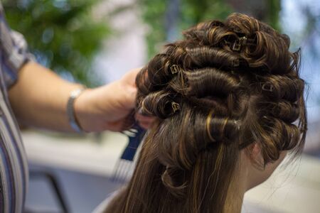 Hairdresser doing a woman's hair in professional hairdressing salon or barbershop , seen from behind the customer, unrecognizable.の写真素材