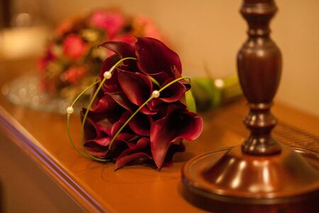 Close-up of two Wedding rings and the wedding bouquet of beautiful red Zantedeschia aethiopica or callas on a weddings day の写真素材