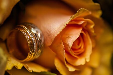 Close-up of two Wedding rings and the wedding bouquet of pink roses on a weddings dayの写真素材
