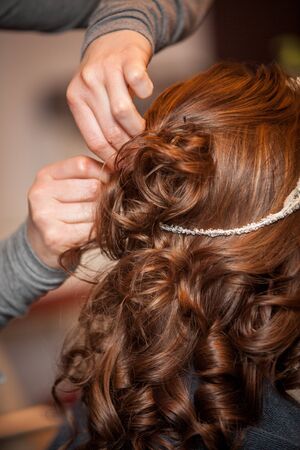 Hairdresser doing a womans hair in professional hairdressing salon or barbershop , seen from behind...