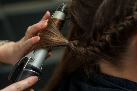 Hairdresser doing a womans hair in professional hairdressing salon or barbershop , seen from behind...