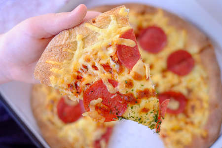 Male Hand takes a slice of Pizza Pepperoni with Mozzarella cheese, tomato, olive and pepperoni....