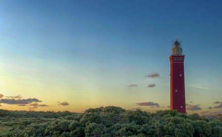 Lighthouse standing on the Dutch coast with a dramatic. and colorful dusk or dawn sky behind it. High quality photoの写真素材