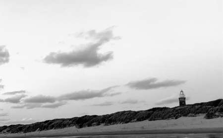 Lighthouse standing on the Dutch coast with a dramatic. and colorful dusk or dawn sky behind it. High quality photo in monochrome, black and whiteの写真素材
