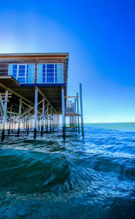 Wooden pylon of Ocean Pie. Surfers and seagulls enjoy the calm ocean waves. High quality photoの写真素材