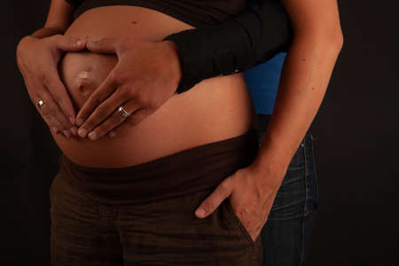 Loving lesbian gay couple with hands around pregnant belly. High quality photoの写真素材