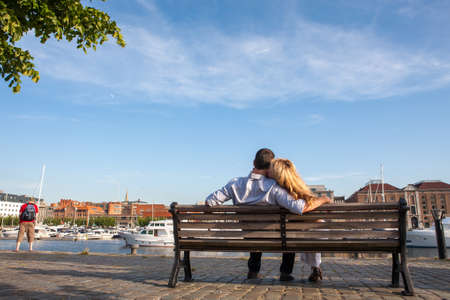 Couple on a bench - Two lovers sitting on a bench in a park and holding themselves by hands - Concepts of autumn,love,togetherness,relationship. High quality photoの写真素材