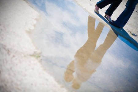 The reflection of the charming hugging couple in the puddle. High quality photo