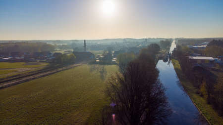 Aerial view of an Idillic river stream canal with grass banks and wild flowers and trees in a scenic...