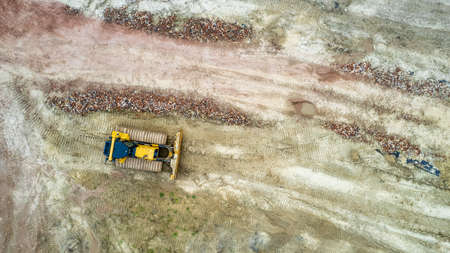 Excavator or bulldozer at work on industrial construction site. Aerial view taken with drone. High...