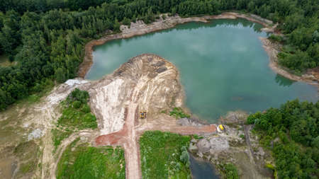 Excavator or bulldozer at work on clay mining site. Aerial view taken with drone. High quality photo