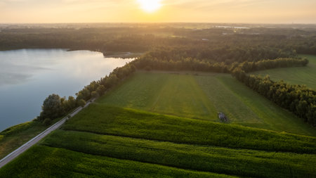 Aerial view with a drone of a spring wavy agricultural countryside landscape with plowed and unplowed fields and trees in the blue evening sky. High quality photoの写真素材