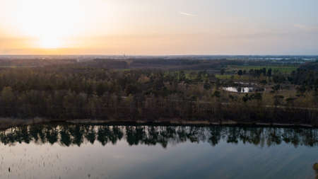 Aerial view shot by a drone of a beautiful dramatic and colorful sunset at coast of the lake. Nature landscape. Nature in Europe. reflection, blue sky and yellow sunlight. landscape during sunrise or sunset. Blakheide, Beerse, Belgium. High quality photoの写真素材