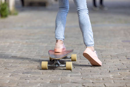Cropped shot of young woman legs in sneakers practice new tricks at skateboarding in park. Sport and urban lifestyle concept. High quality photoの写真素材