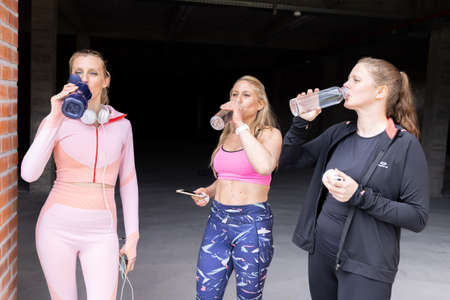 Sporty beautiful young women of different body types drinking water from bottle after working out...