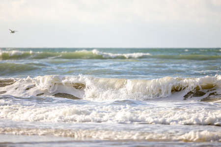 Crashing waves lapping on the sandy beach one after another under a blue sunset sky, selective focus...