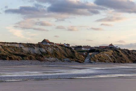A colorful, dramatic ocean sunset, landscape with a small town on a cliff in the background at the shore of Cap Blanc-Nez, France. High quality photoの写真素材