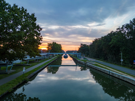 Aerial view of a colourful dramatic sunrise sky over a canal with a cargo boat in Belgium. Canals with water for transport, agriculture. Fields and meadows. Landscape aerial view shot from a drone. High quality photoの写真素材