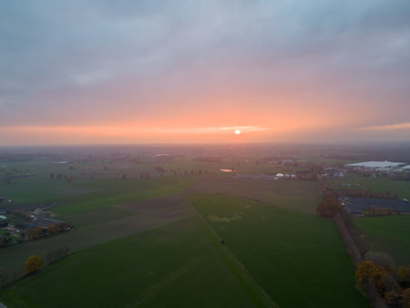 Aerial view of endless lush pastures and farmlands of Belgium under a dramatic colorful sunset sky. Beautiful antwerp countryside with emerald green fields and meadows. Rural landscape on sunset. High quality photoの写真素材