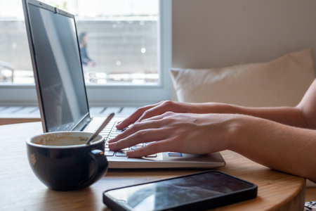 Close up side view of female using her laptop at a cafe. Lateral shot of young woman sitting at a...