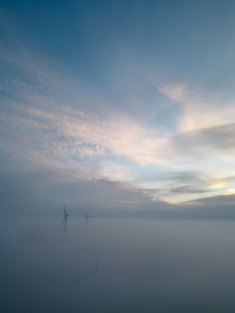 Aerial view of wind turbines or windmills farm field in industry factory with fog. Power,...