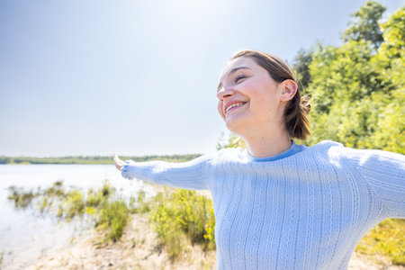 Free Happy Woman Enjoying Nature on a forest lake. Beauty Girl Outdoor. Freedom concept. Beautiful attractive Girl over Sky and Sun. Sunbeams. Enjoyment. High quality photoの写真素材