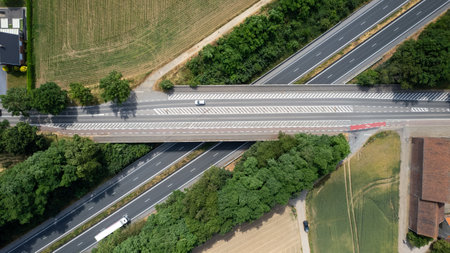 Aerial view of the road with bridge over a highway and forest and fields next to it on a summer sunny day. Highway in Belgium. High quality photoの写真素材