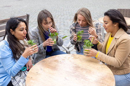 A lively image featuring a multi-ethnic group of female friends savoring refreshing Mojito cocktails...