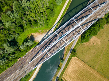 An awe-inspiring aerial perspective of a steel railroad bridge gracefully spanning over a serene...