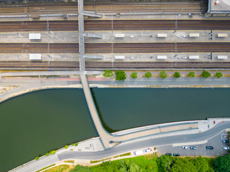 This stunning top down aerial view reveals the intricate layout of several railway tracks next to a waterway, highlighting the beautiful coexistence of land and water transport routes. Railway Meets Waterway: Aerial View of Train Tracks. High quality photoの写真素材