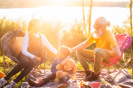In this heartwarming image, three generations come together in a serene lakeside setting, basked in...