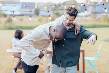 A joyful interaction is frozen in time as a Black man bursts into laughter, leaning forward with...